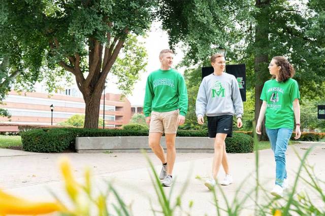 Students walk along a campus pathway beneath mature trees near the Science Building at Marshall University.