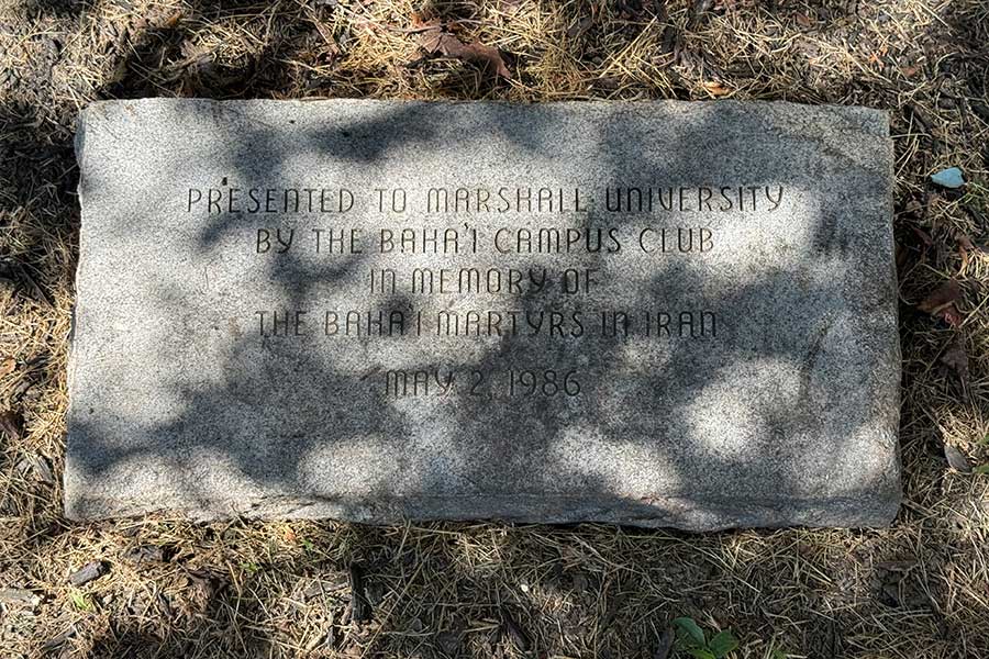 Stone memorial marker at the base of the Baháʼí Martyrs Memorial Tree inscribed, “Presented to Marshall University by the Baháʼí Campus Club in memory of the Baháʼí martyrs in Iran, May 2, 1986.”