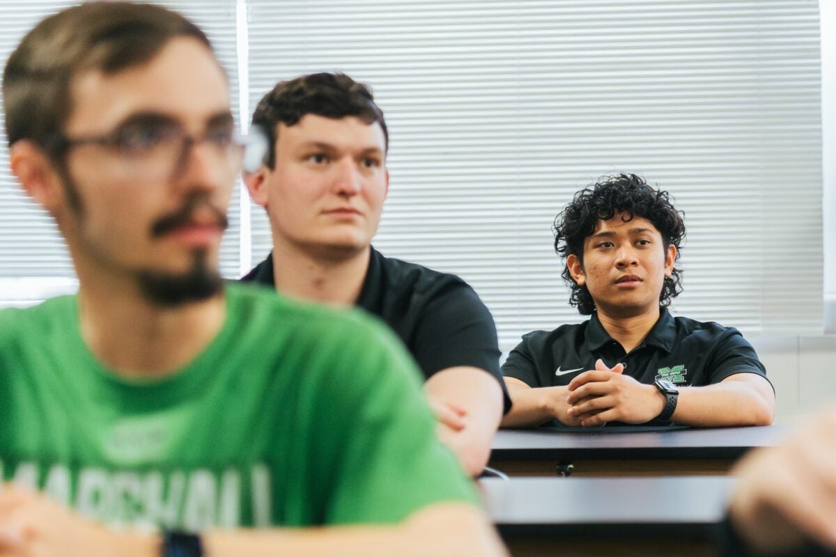 three students sitting in a class listening to a lecture