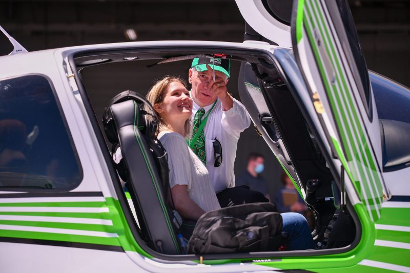 A Marshall University aviation instructor speaks with a prospective student seated inside a Marshall branded aircraft during an aviation event