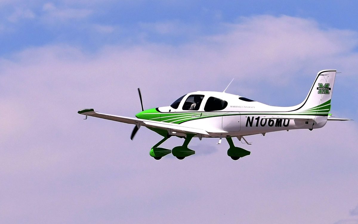 A Marshall University branded plan flies through a cloudy sky