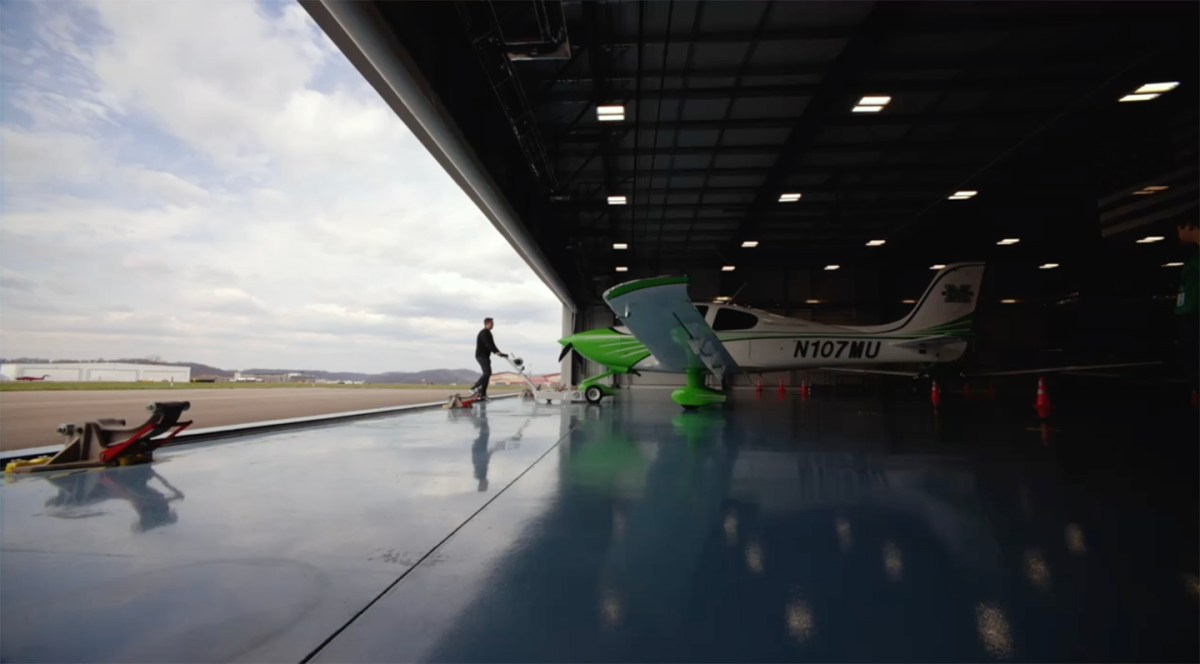 An aviation students pulls a Marshall branded plane of of the hanger