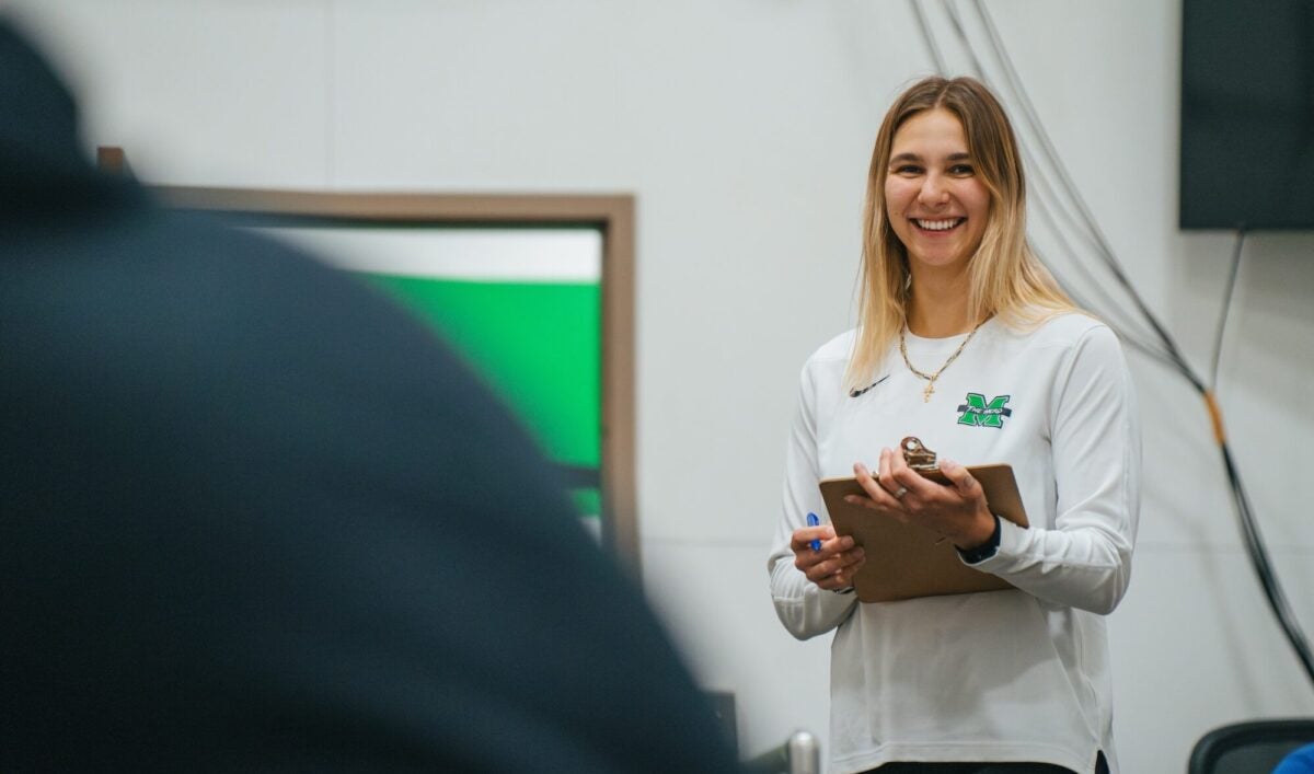 student holding a clip board and smiling in the biomechanics-dev lab