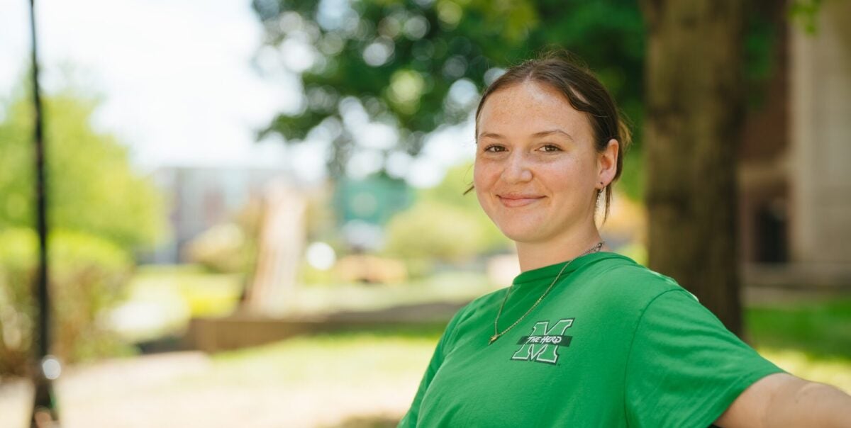 student outside on campus on a bench smiling at the camera