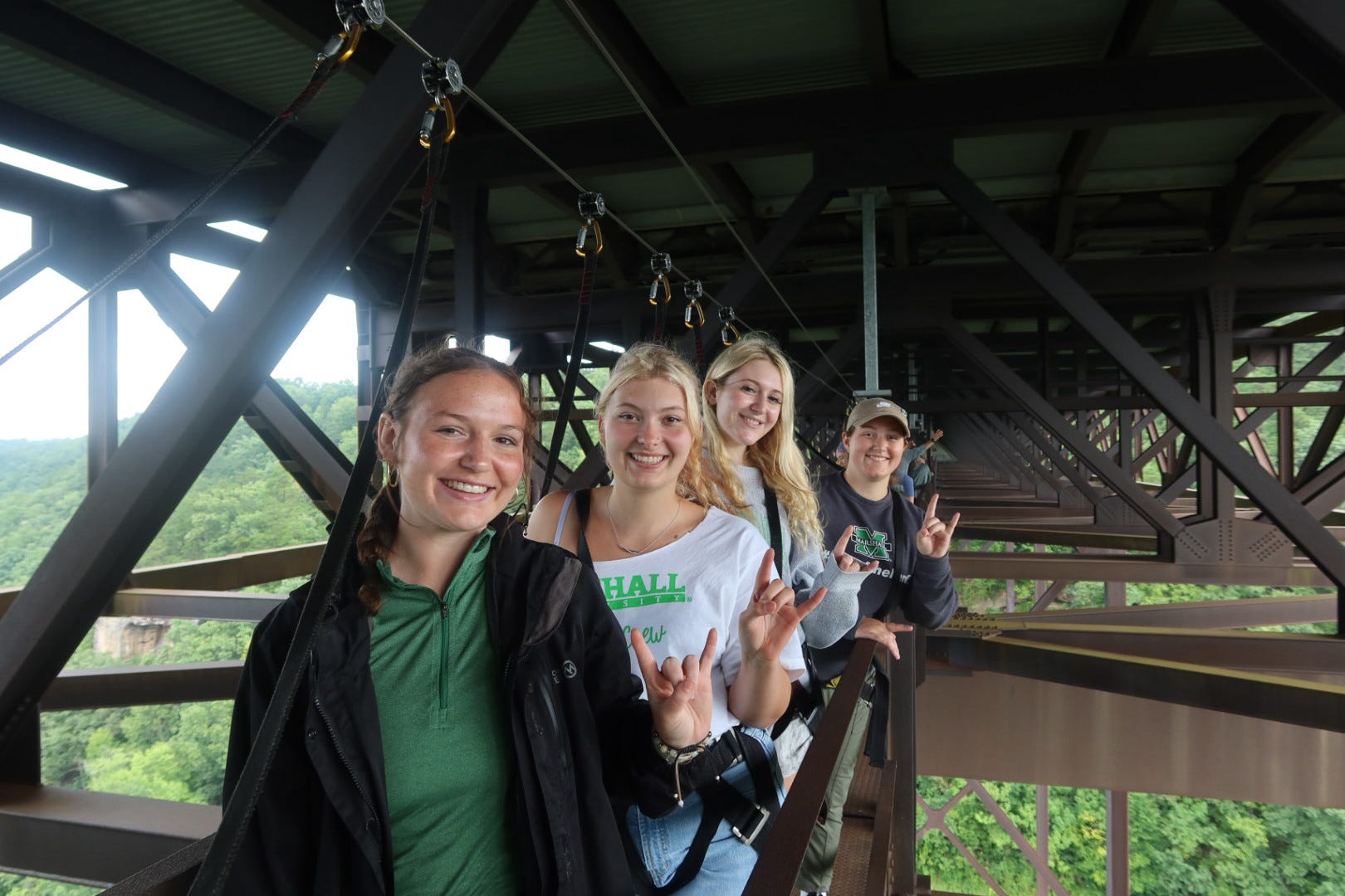 Scholars smiling and showing the Go Herd sign on the bridge walk
