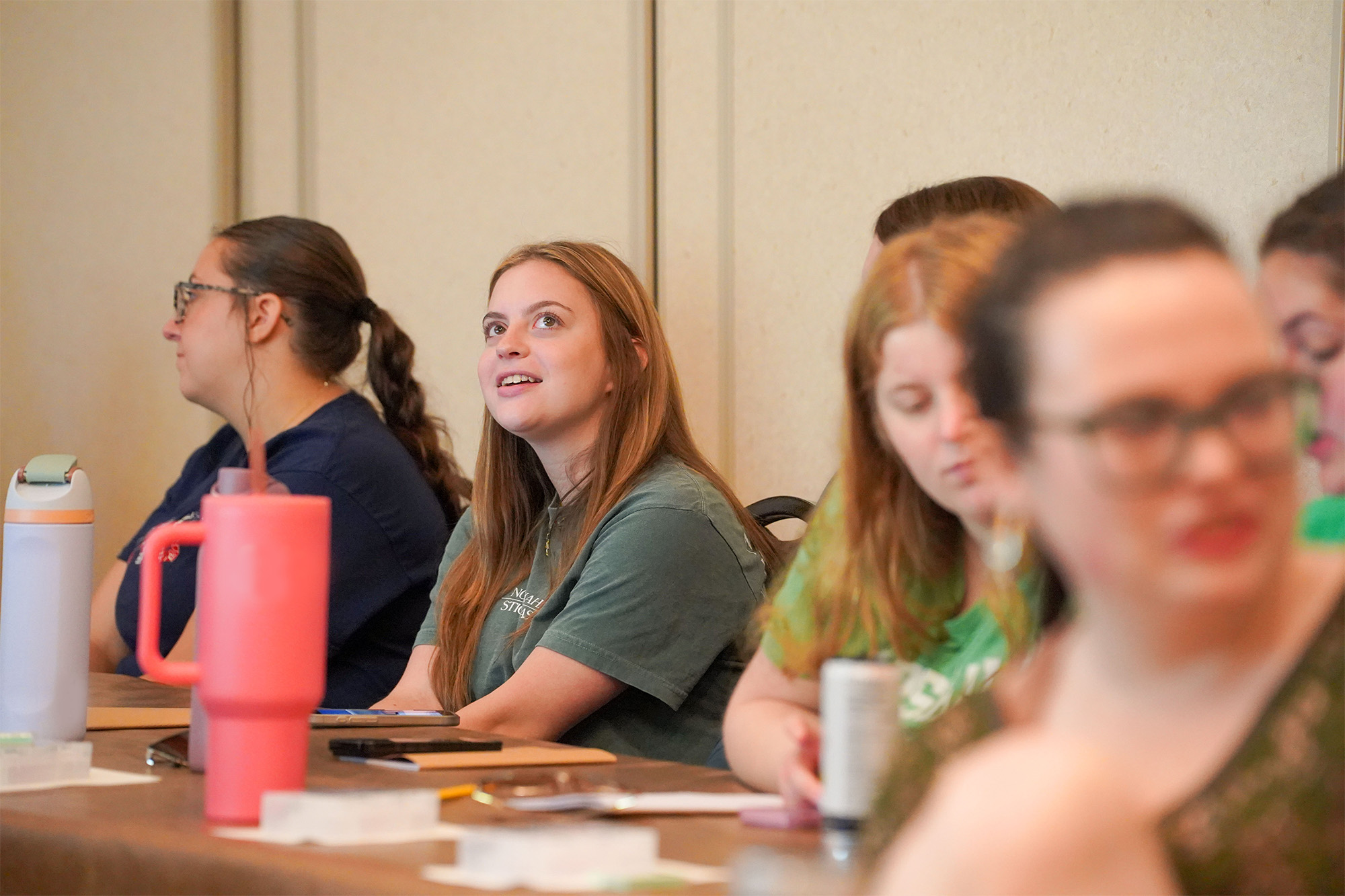 student looking to the ceiling thinking, with other students sitting at a desk