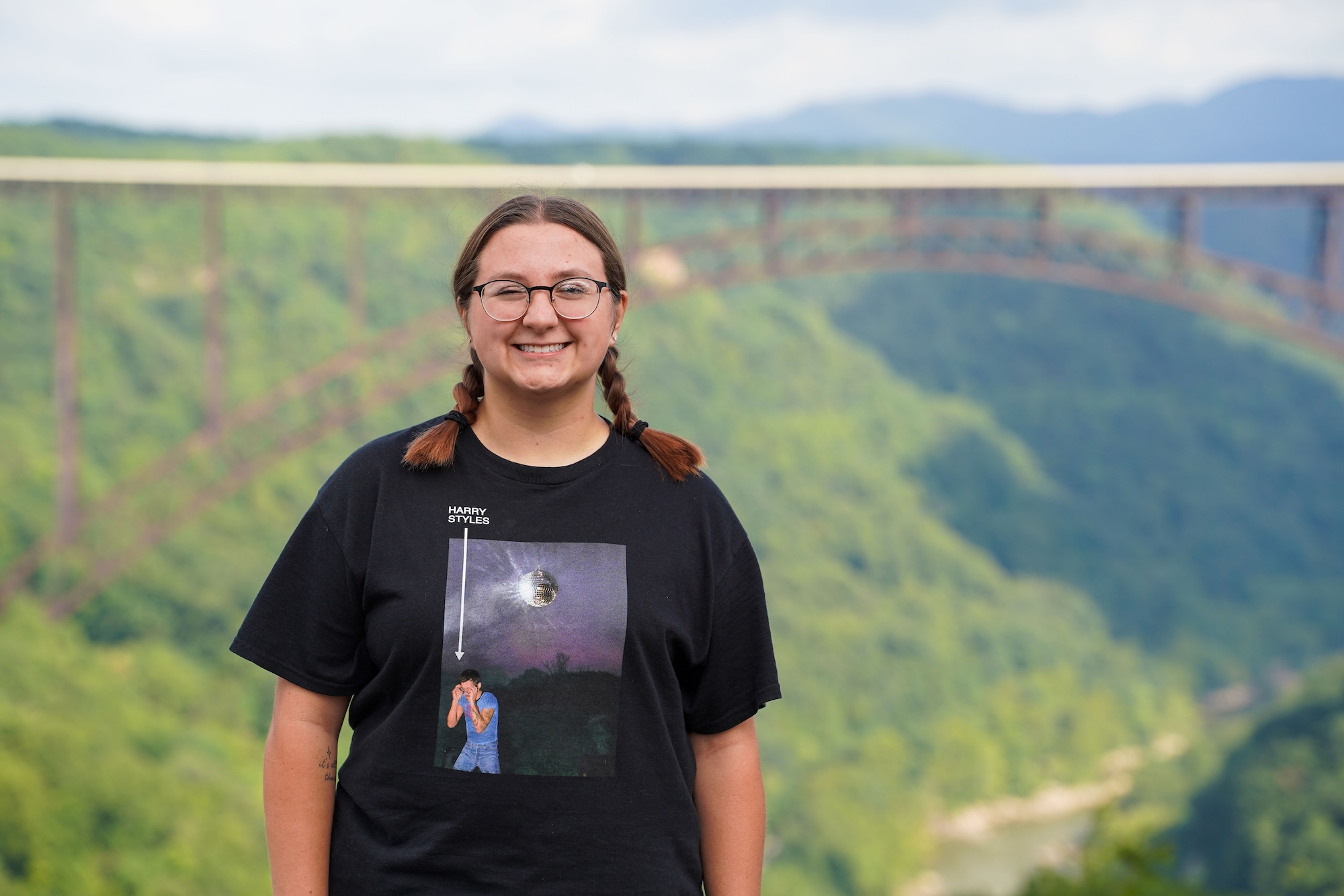 student smiling in front of the New River Gorge Bridge