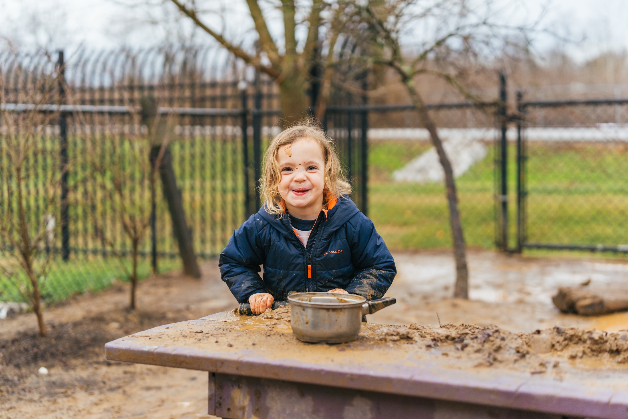 toddler playing in a mud kitchen outside