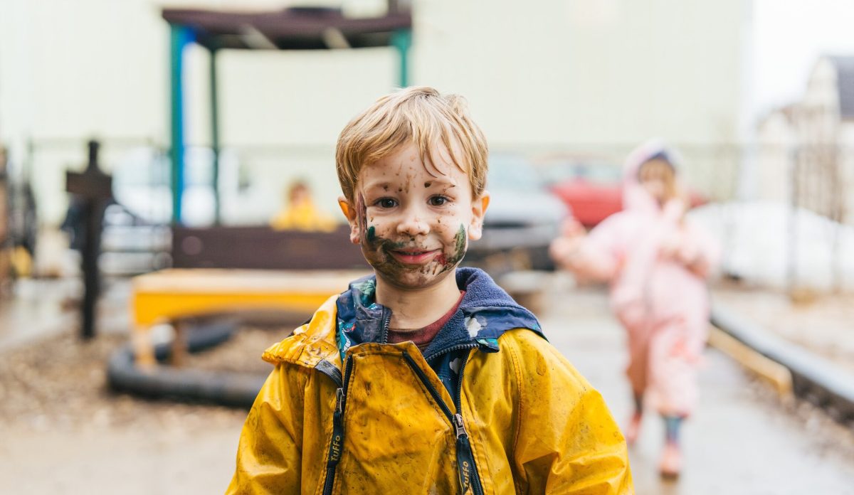 toddler outside in the mud with paint on his face