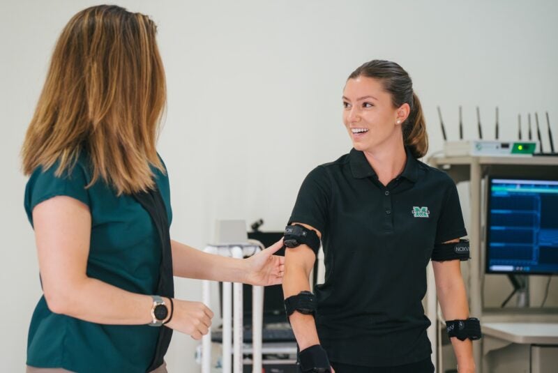 one person getting assessed by a professor in a physical therapy lab