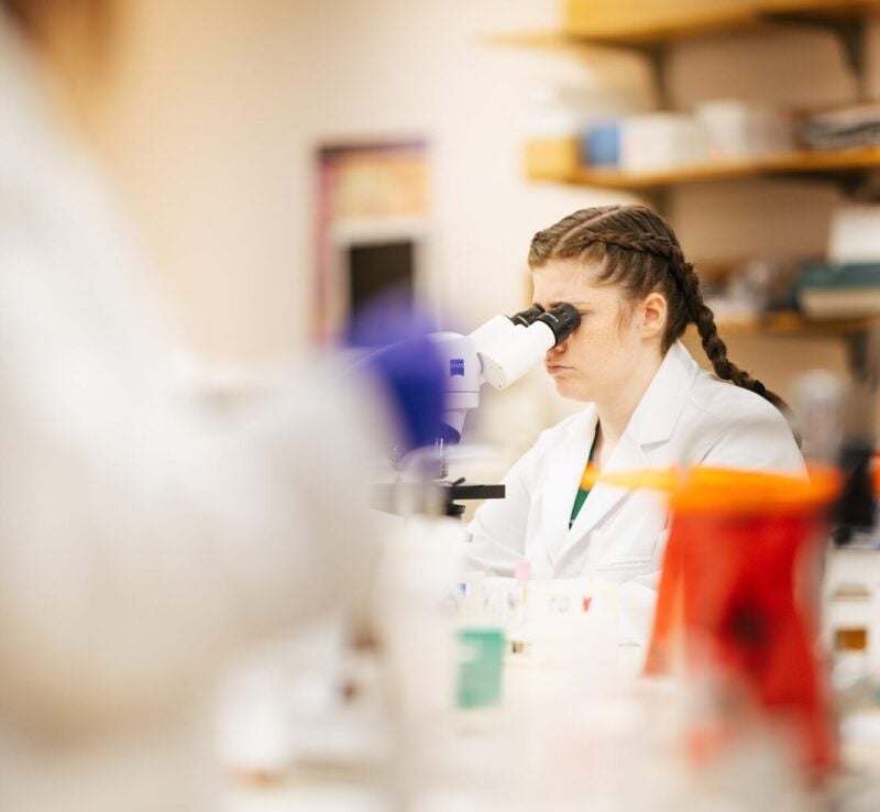 student looking through a microscope in a lab
