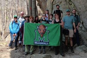 Biology plants group takes a moment to pose with a Marshall flag while exploring Wildflower Weekend at Carter Caves State Park