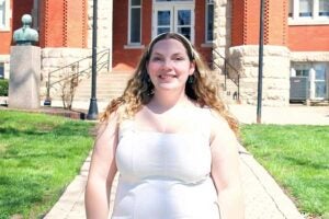 Criminal Justice student Matison Brown standing proud in front of Old Main's iconic west entrance