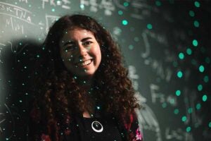 Two-time Marshall University physics graduate Ellie White stands in front of a chalkboard covered with physics equations and diagrams, while green laser dots projected across the scene create a starfield effect.