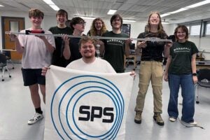 Members of Marshall University's Society of Physics Students chapter pose with an SPS banner and a demonstration apparatus during a planning meeting for the 2026-27 academic year.