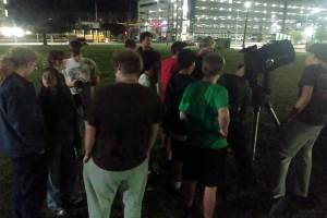 Students gather around a telescope during an evening Astronomy Club stargazing event on Marshall University’s campus, taking turns observing Saturn and the night sky.