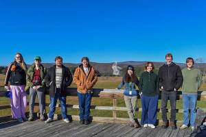 Marshall University physics students stand on an observation deck at Green Bank Observatory with the Robert C. Byrd Green Bank Telescope visible in the distance against a mountain backdrop. The visit provided students with hands-on experience in radio astronomy and telescope operations.