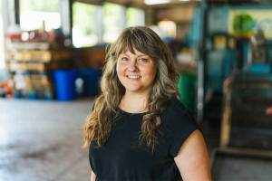 Amy Parsons-White, Sustainability Manager, stands inside Marshall University's composting facility, with equipment and work areas visible in the background