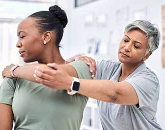 Chiropractic adjustment session showing a practitioner guiding a patient’s arm and shoulder through a controlled movement