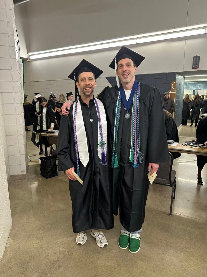 Photo of two individuals in commencement cap and gown