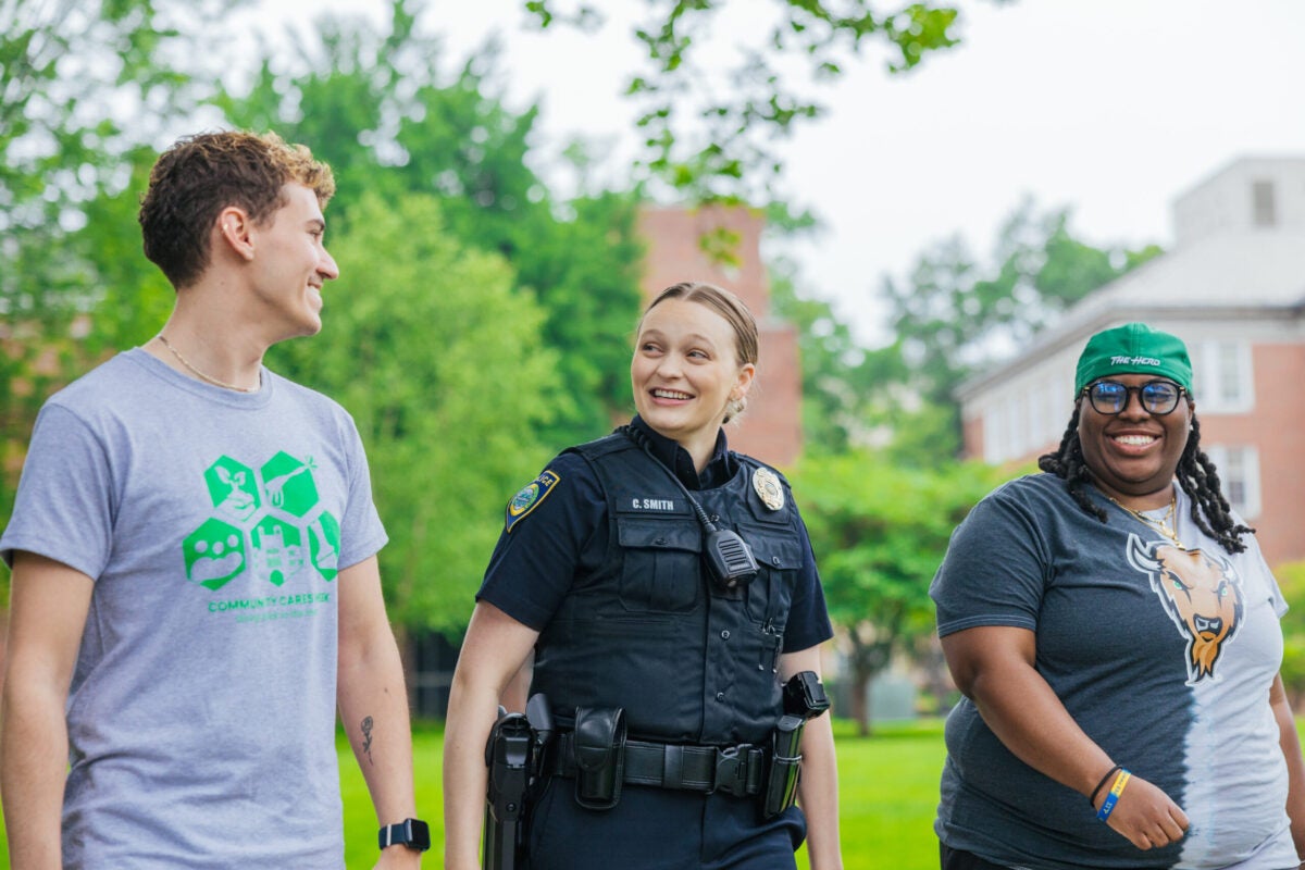 two students walking with a police officer on campus