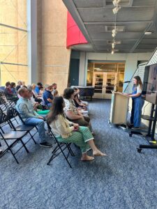 girl reading her story at a podium to an audience in a library