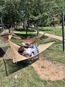 girl writing in hammock outside