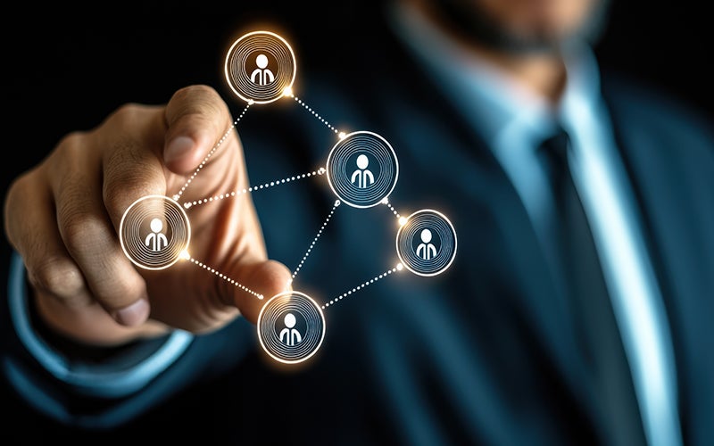 A man in a suit expands a digital graphic on clear glass in front of him