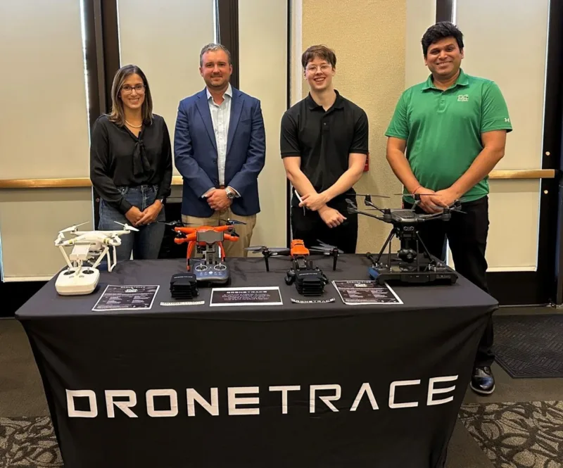 Partners stand behind a table with DroneTrace logo on the front