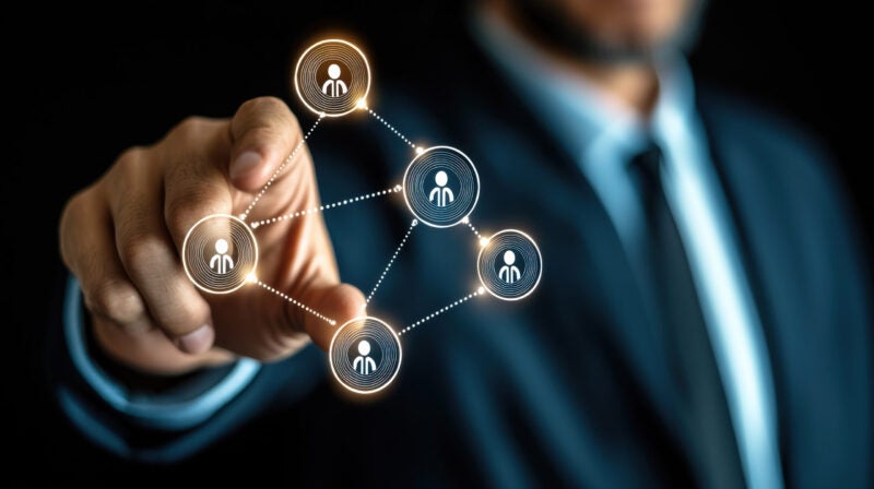 A man in a suit expands a digital graphic on clear glass in front of him