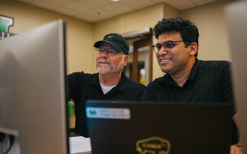 Cyber professionals smile together while looking at a computer screen