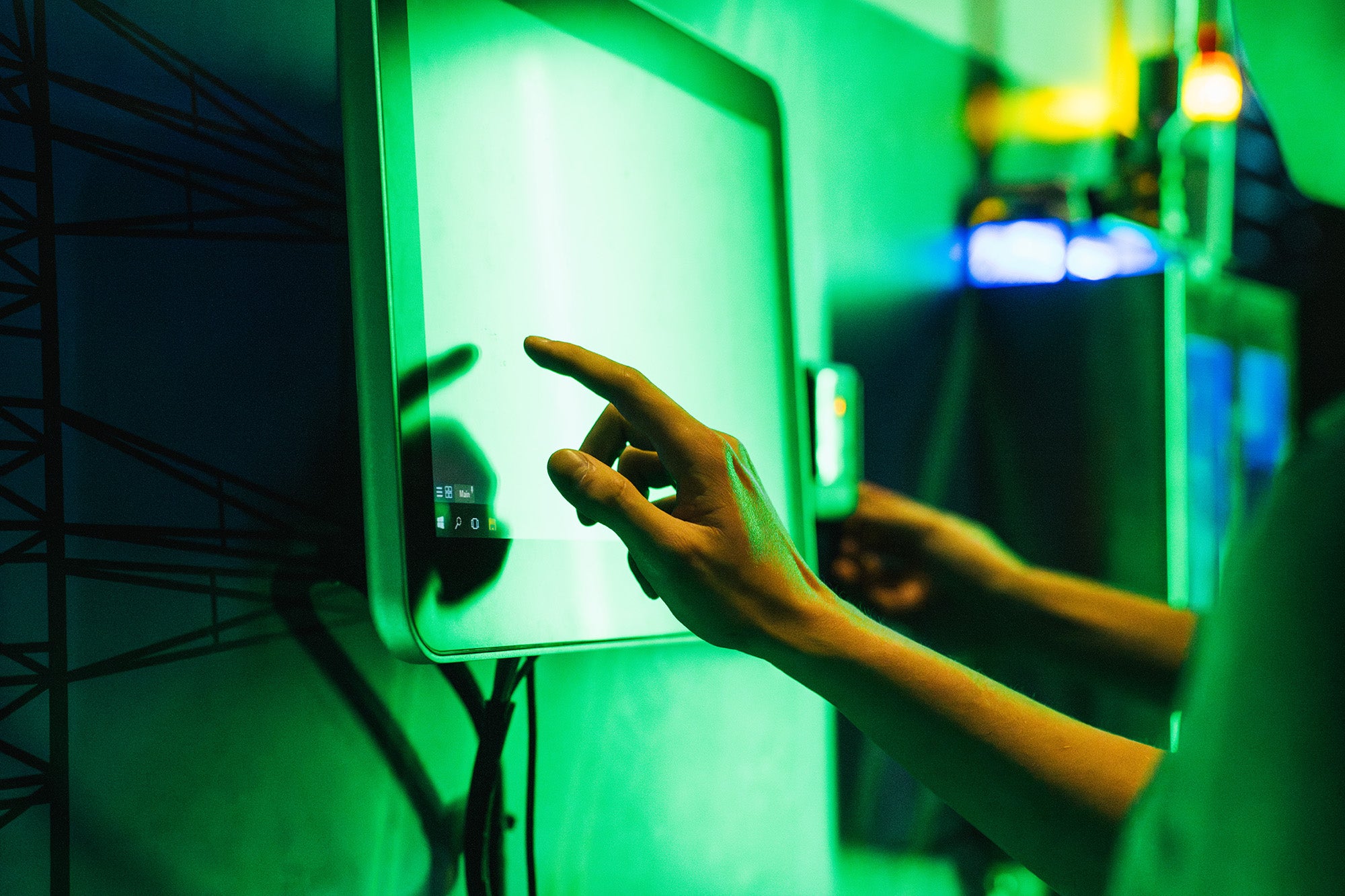 A hand uses a touch screen in a dark space lit by green lights