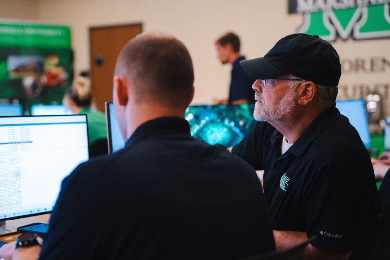 Two men work on a computer in a lab