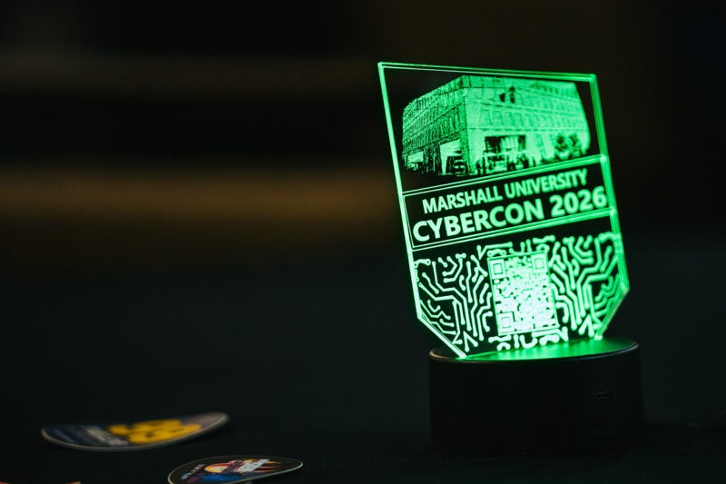 A glass sign is lit in neon green with CyberCon 2026 information