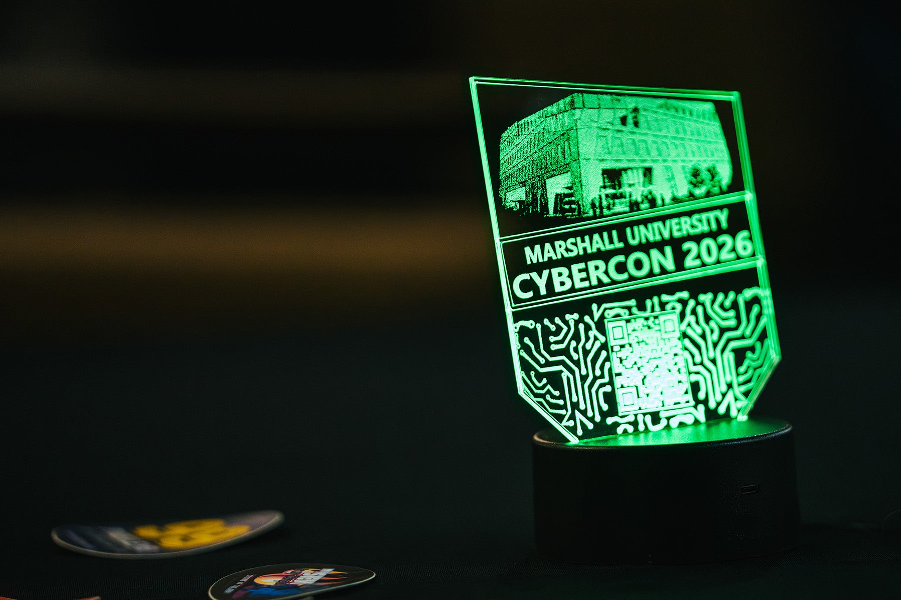 A glass sign is lit in neon green with CyberCon 2026 information
