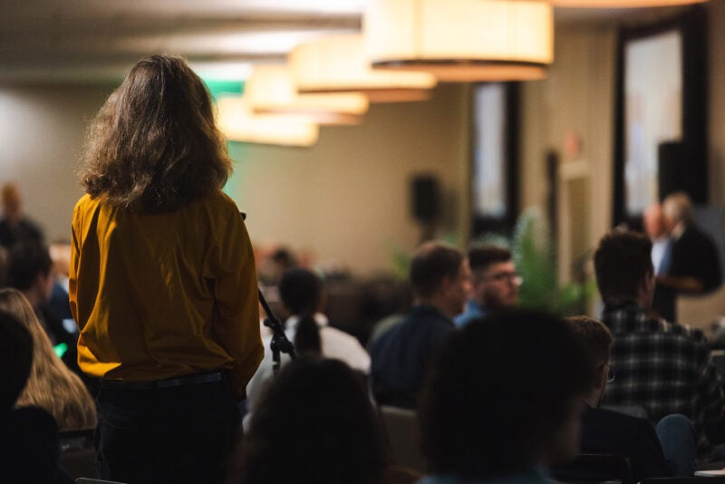 A participant stands to ask a question during a CyberCon session