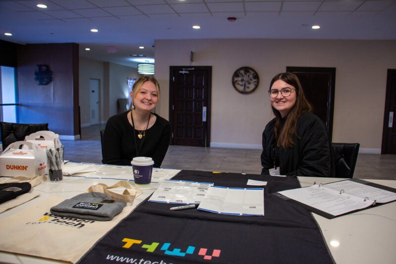 Students sit together at a registration table at a Women and Tech Conference