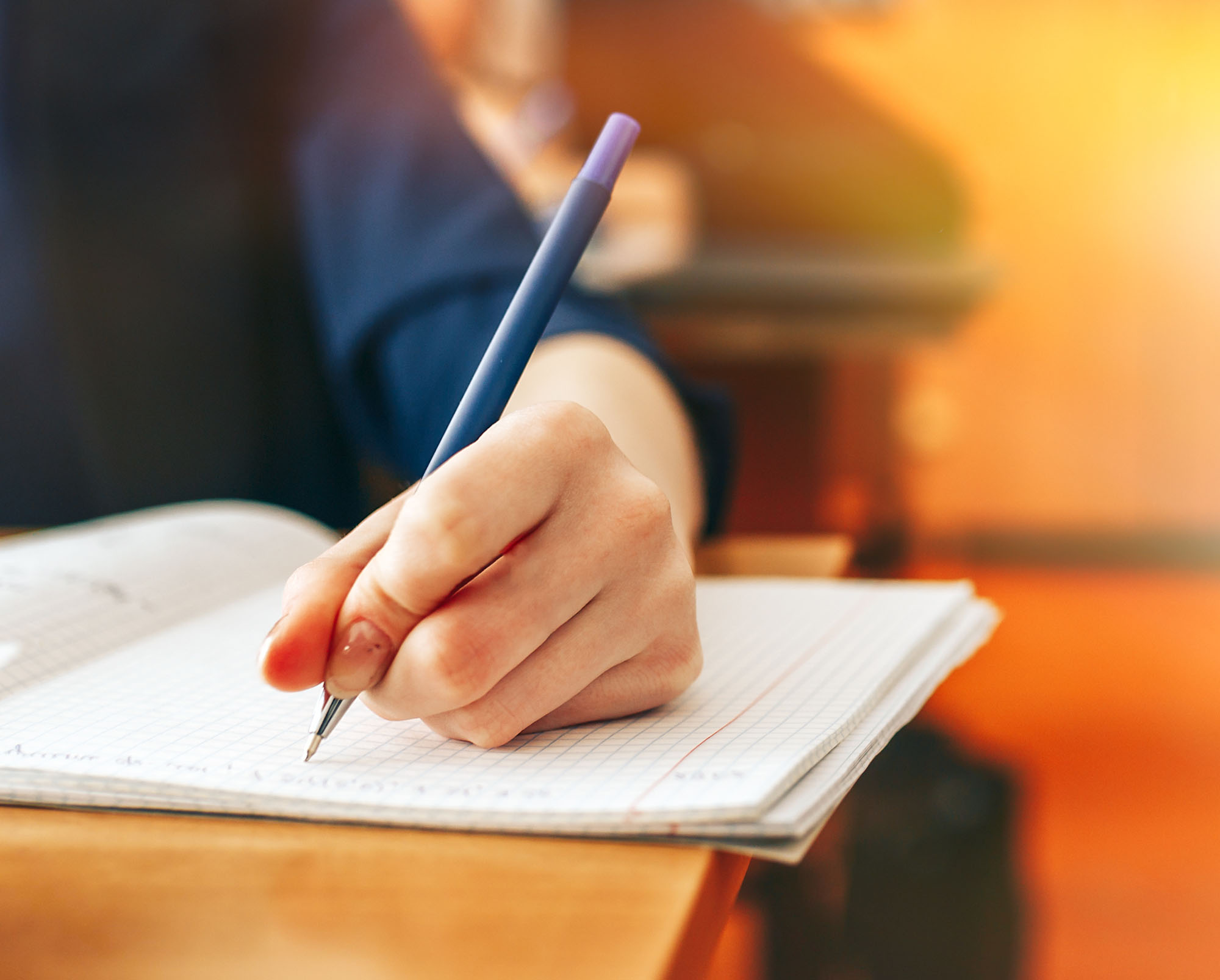 Image of a student writing with a pen
