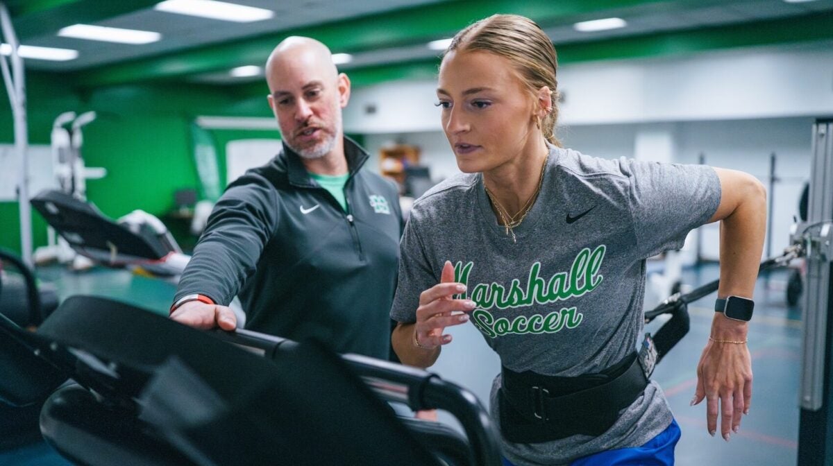 student running on a treadmill with a professor instructing her