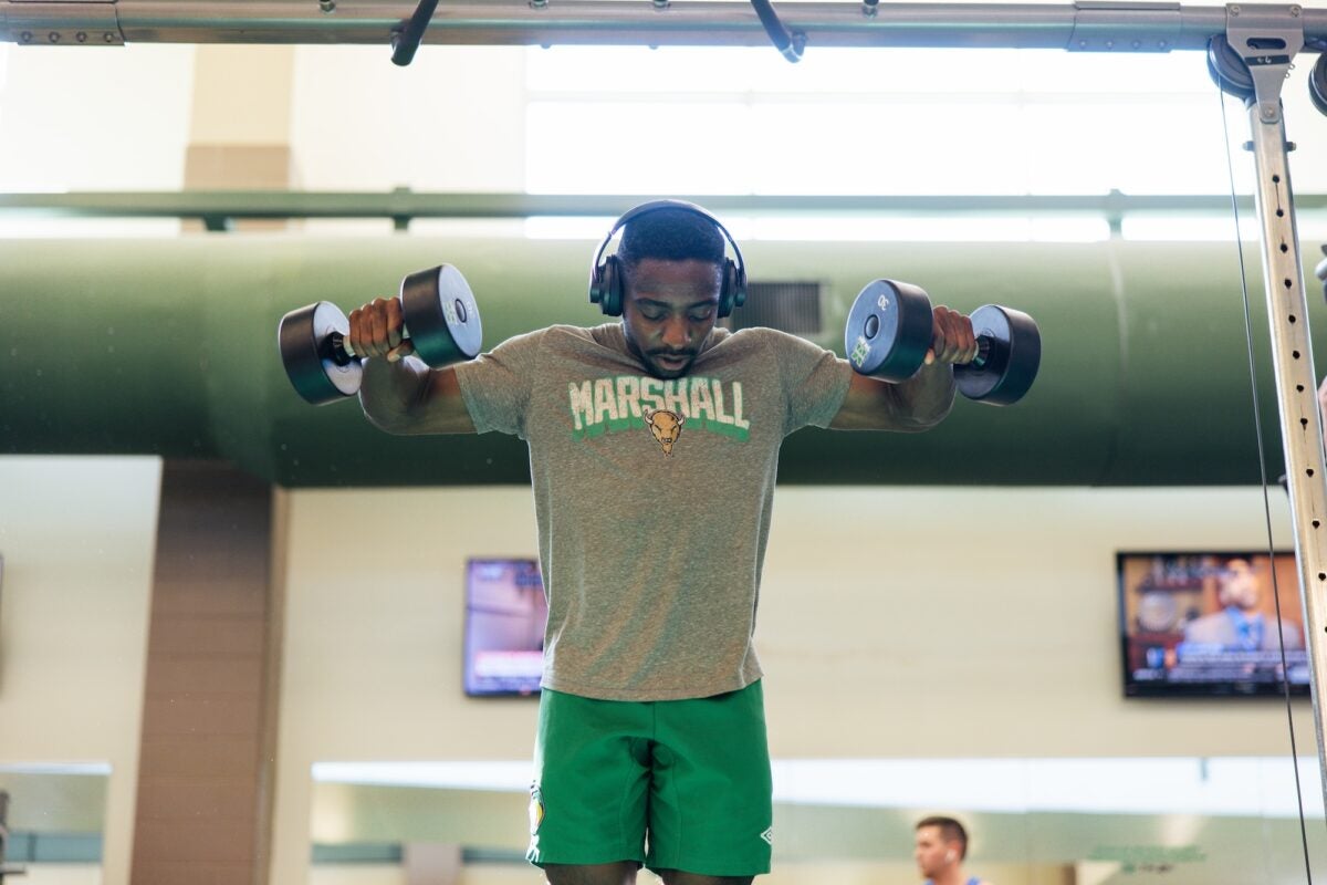 student lifting weights in the rec center with headphones on