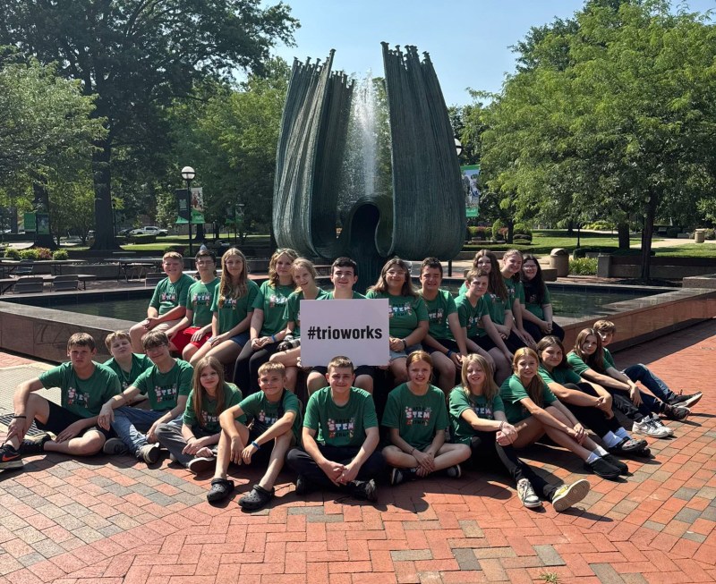 group of middle school students by the Memorial Fountain with a sign that reads 