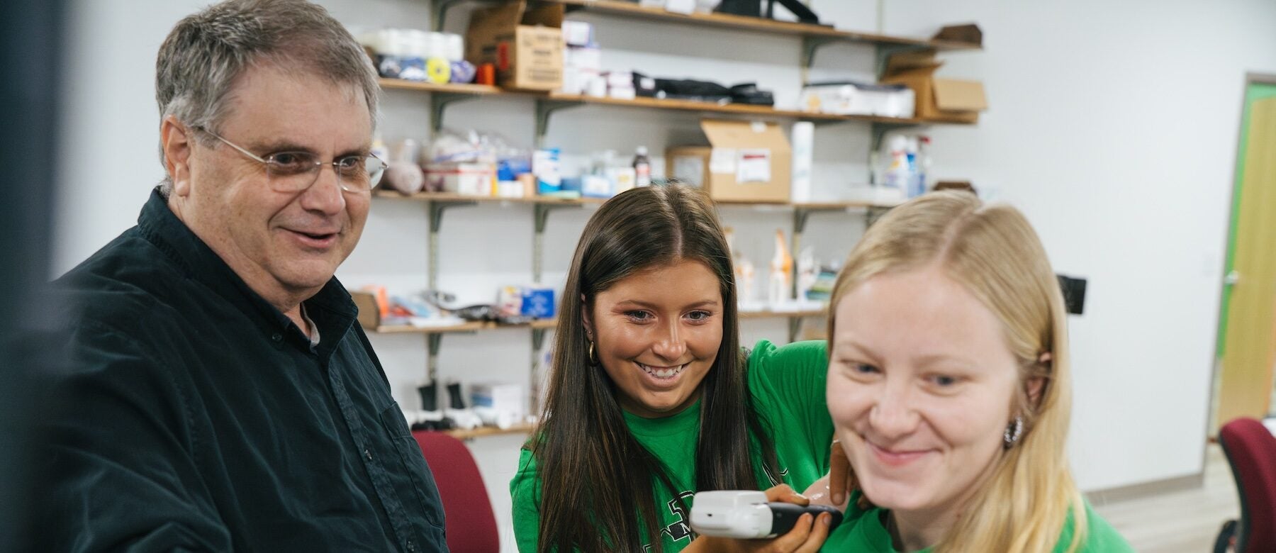students working with a professor on a computer