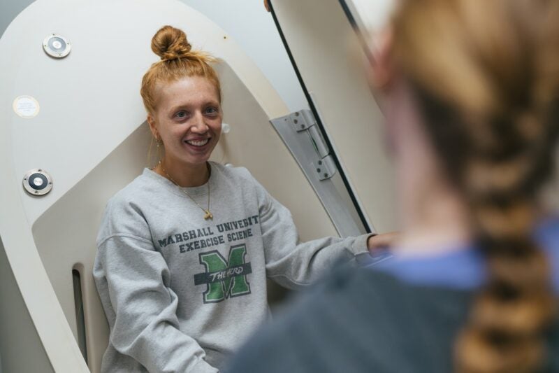 student sitting in a pod in an exercise science sweatshirt