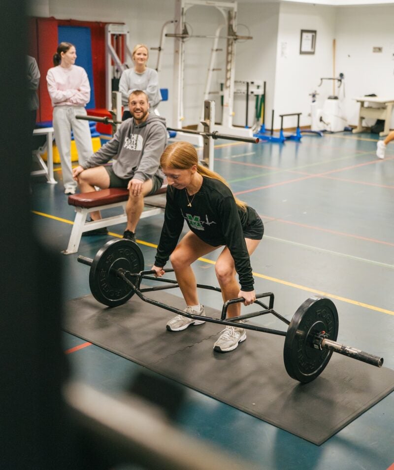 student lifting weights in the exercise science lab