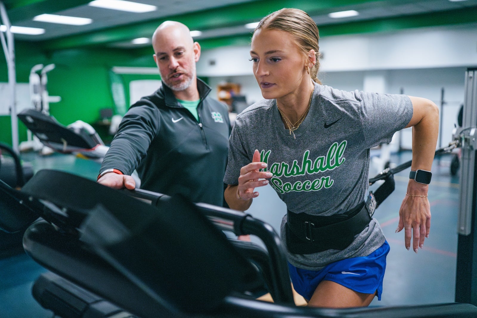 student running on a treadmill with a professor supervising