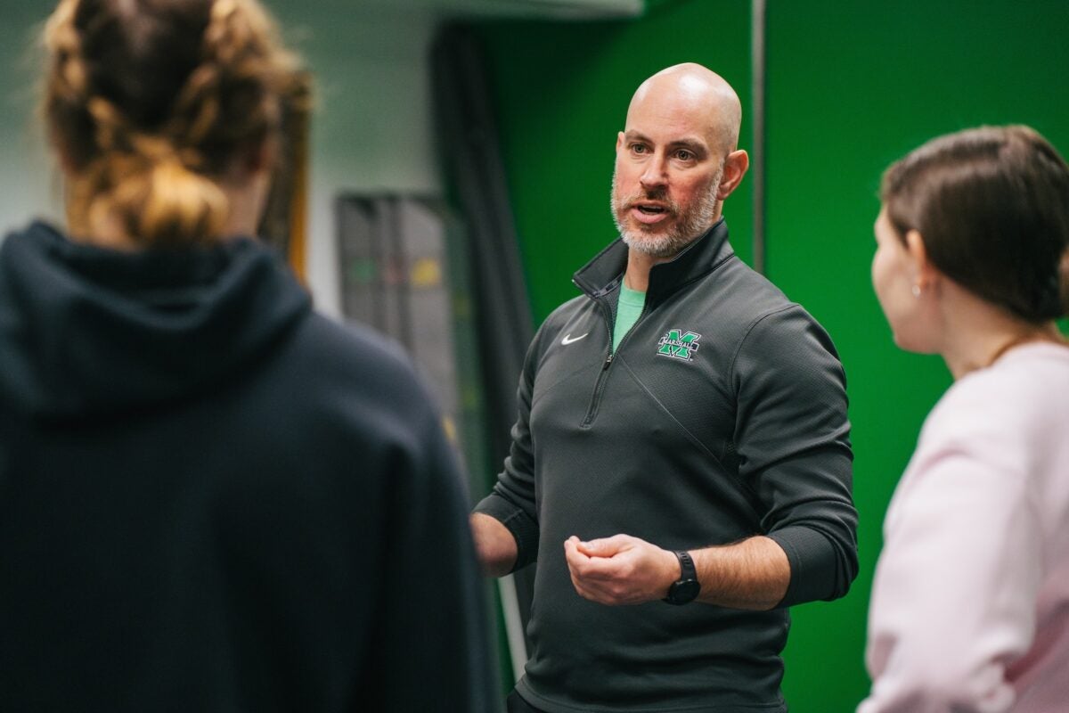 professor explaining a concept to two students in a lab