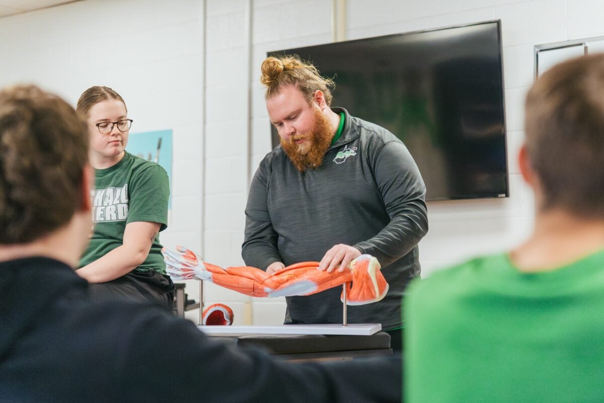 students working on a model of an arm on a table