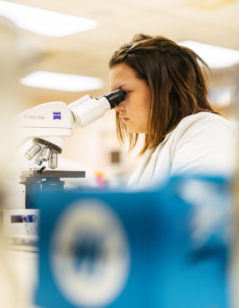 student looking through a microscope in a lab