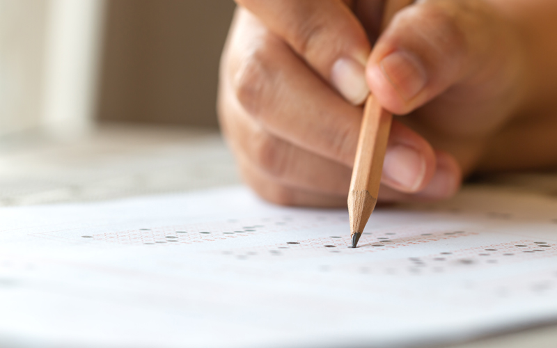 Hand holding a pencil filling in circles on a testing sheet