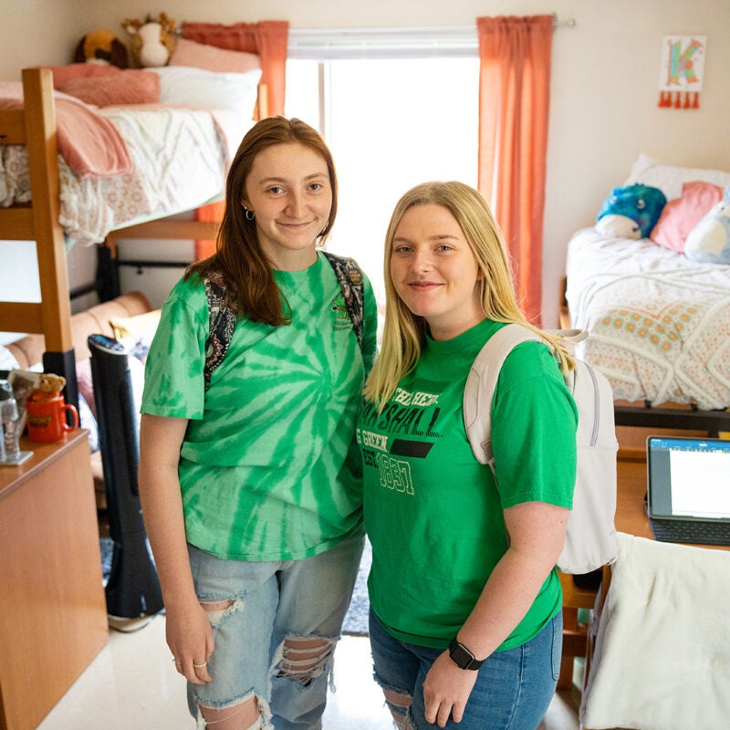 Two students smile together in their decorated dorm room